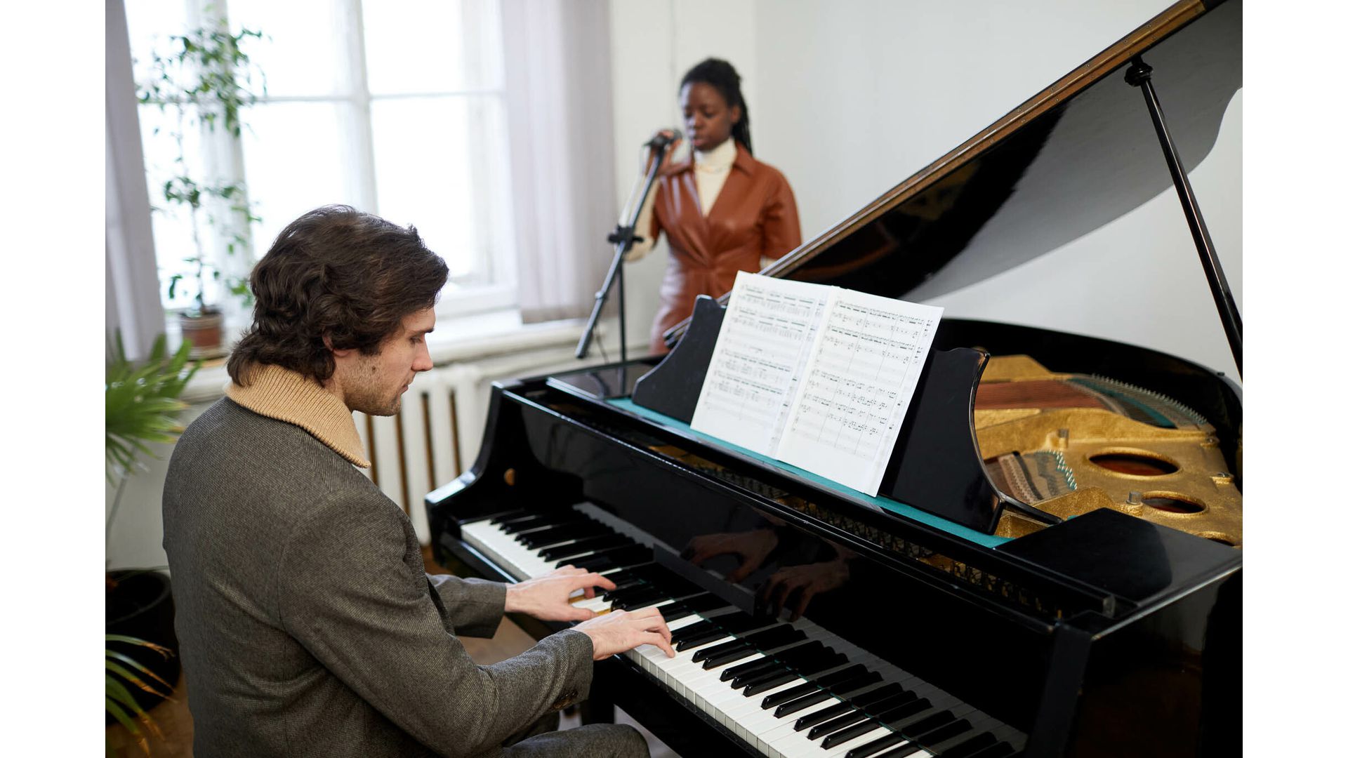 Person playing acoustic piano with singer