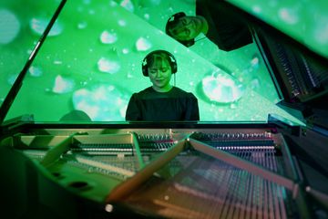 Woman playing a TransAcoustic grand piano with headphones